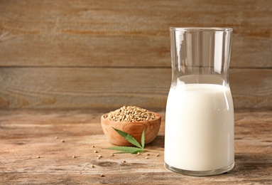 Composition with glassware of hemp milk on wooden table. Space for text