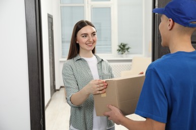 Photo of Courier giving parcel to young woman indoors