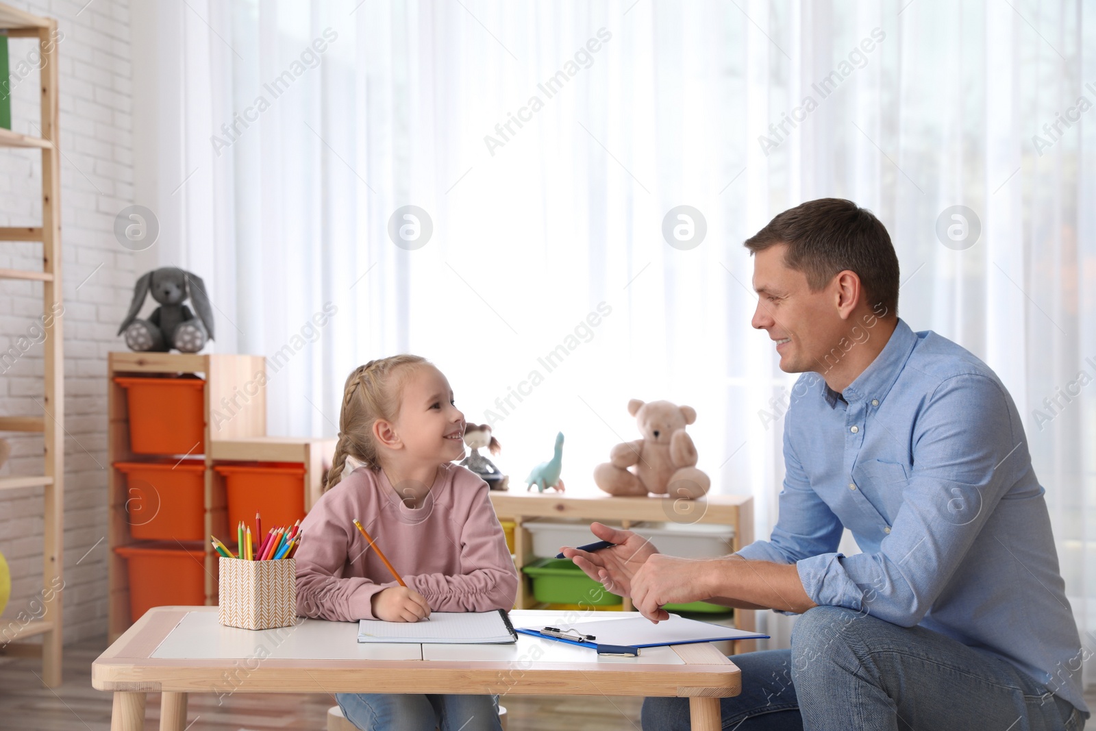 Photo of Child psychotherapist working with little girl in office