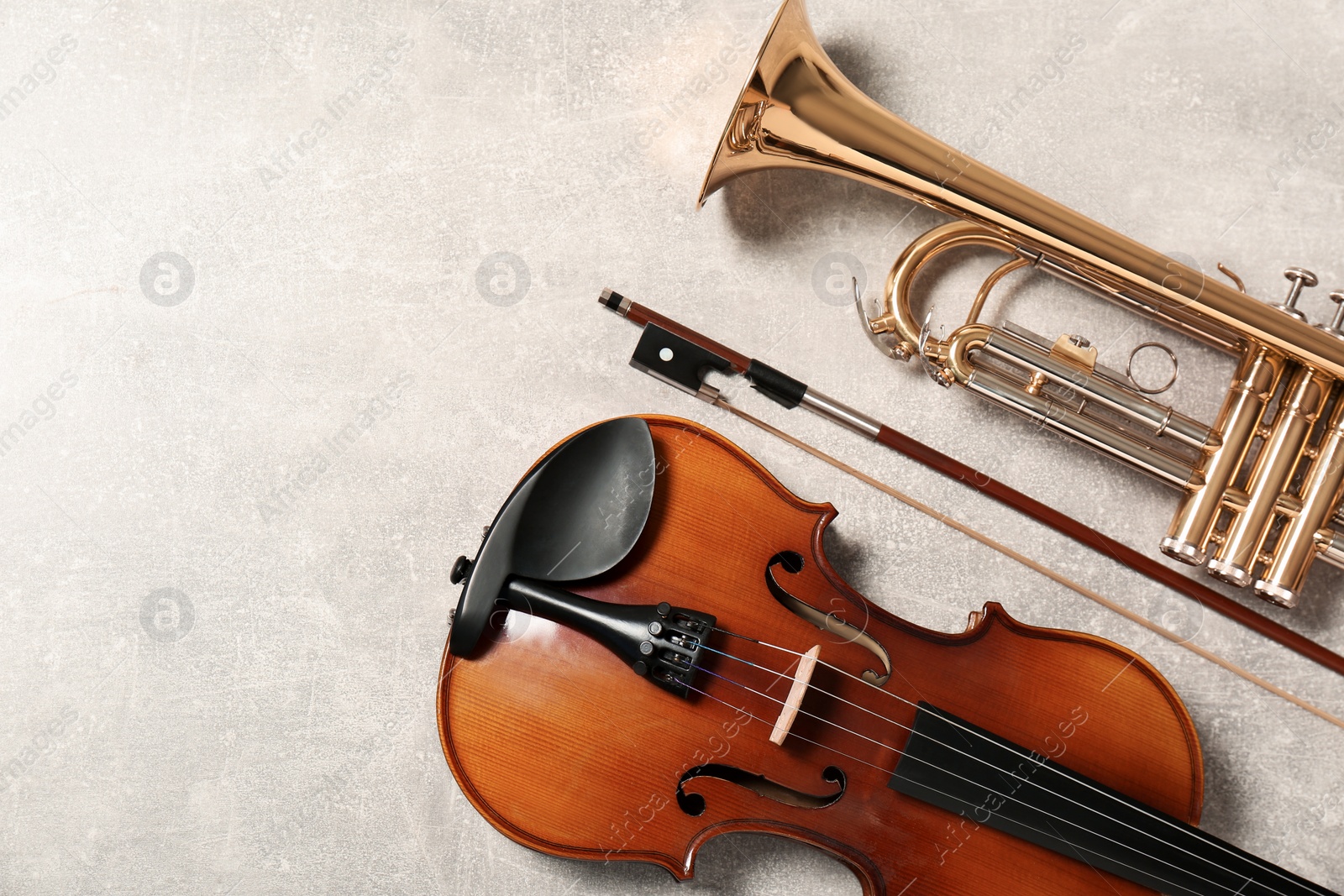 Photo of Violin and trumpet on light grey background, flat lay with space for text. Musical instruments