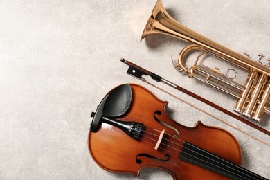 Violin and trumpet on light grey background, flat lay with space for text. Musical instruments