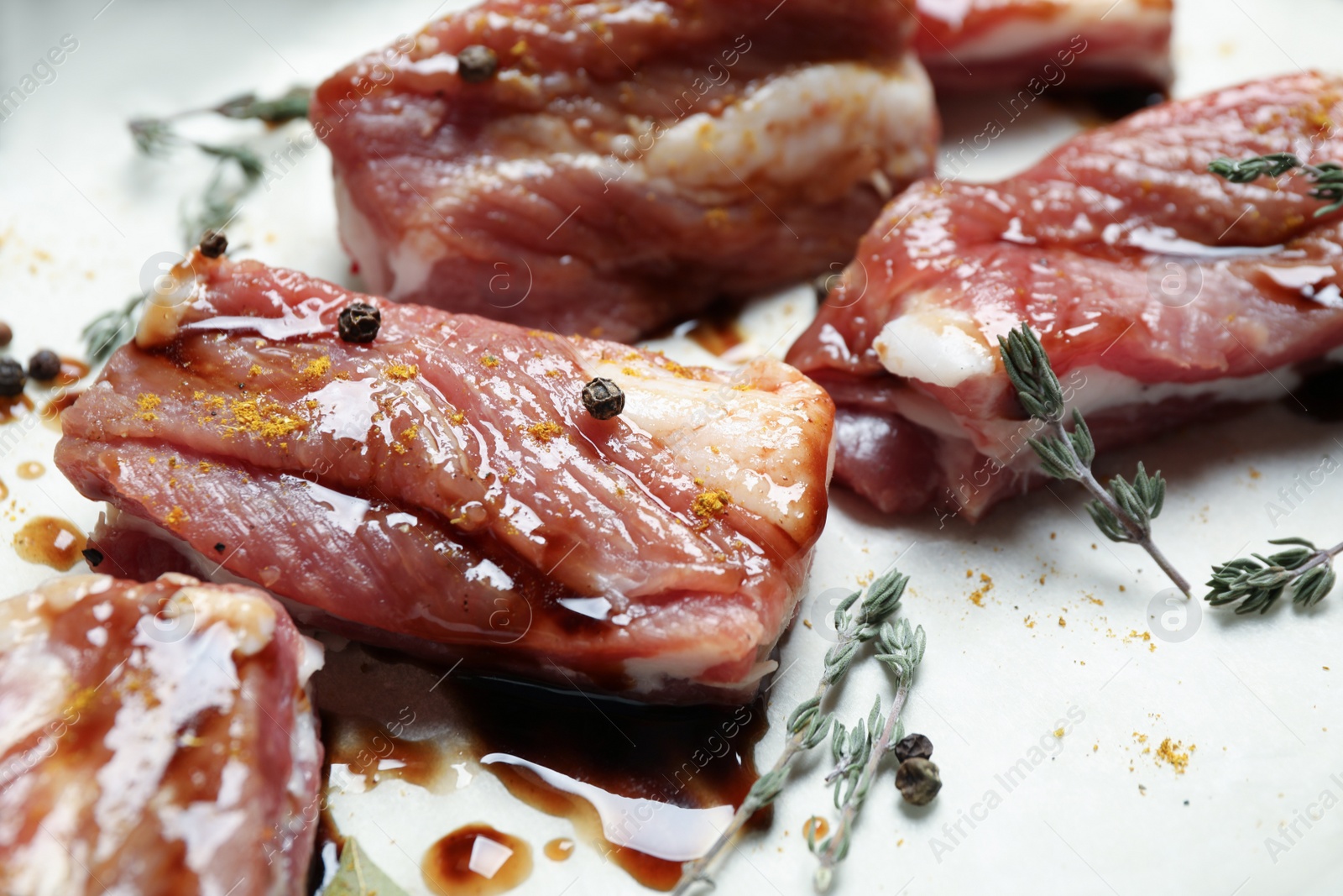 Photo of Raw marinated ribs with thyme and peppercorn, closeup