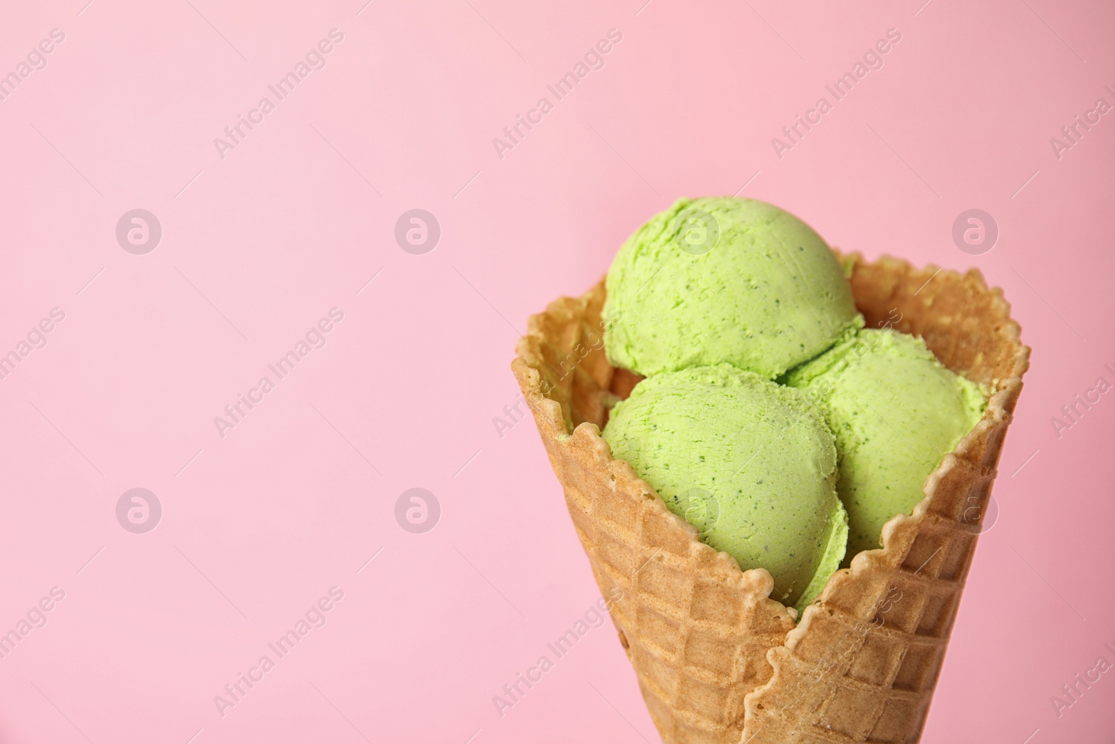 Photo of Delicious ice cream in waffle cone on color background, space for text