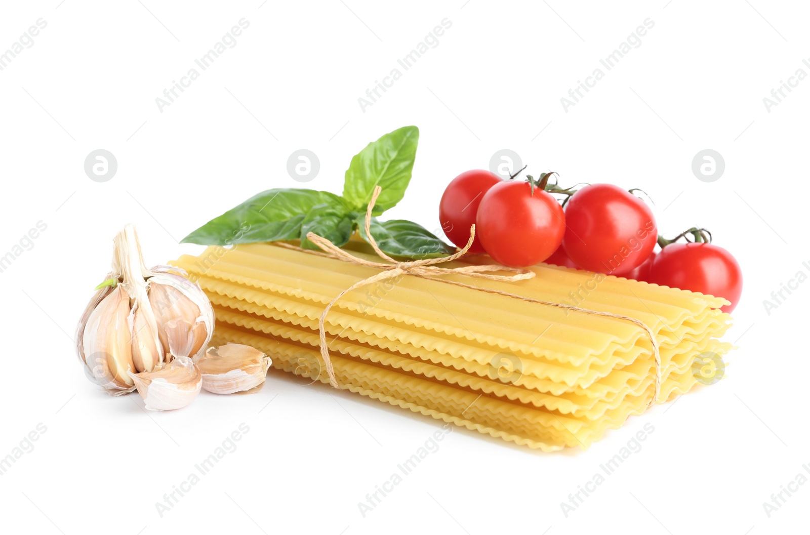 Photo of Uncooked lasagna sheets with cherry tomatoes, garlic and basil isolated on white