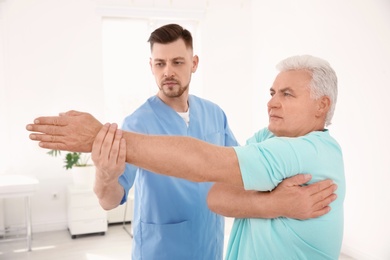 Young physiotherapist working with senior patient in clinic