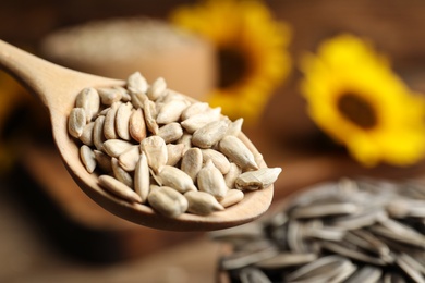 Photo of Wooden spoon with raw peeled sunflower seeds, closeup