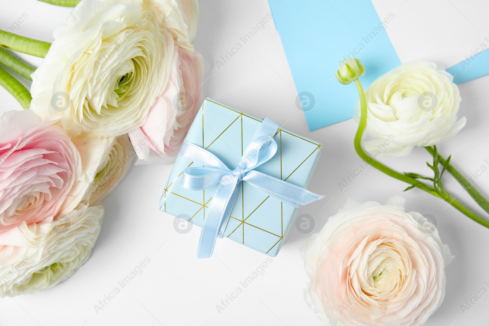 Photo of Composition with gift box and ranunculus flowers on white background, top view