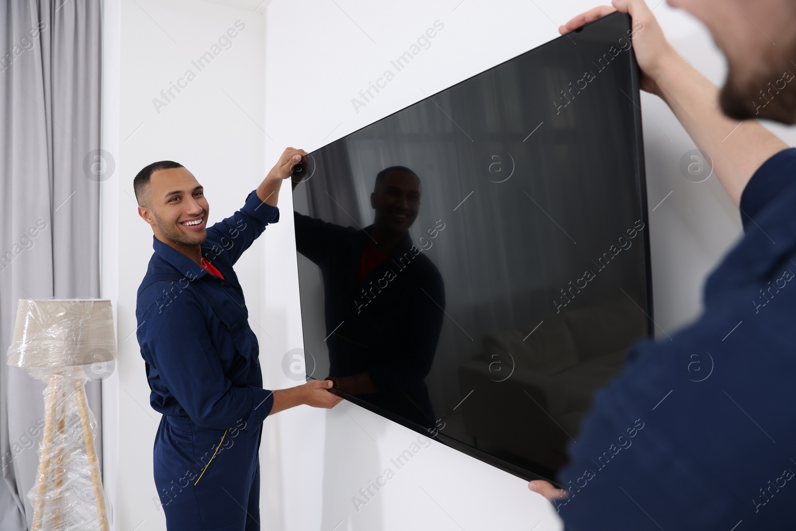 Photo of Male movers carrying plasma TV in new house