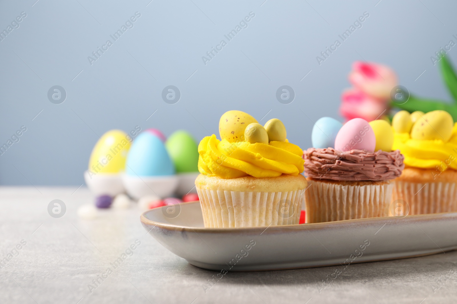 Photo of Tasty decorated Easter cupcakes on grey table, closeup. Space for text