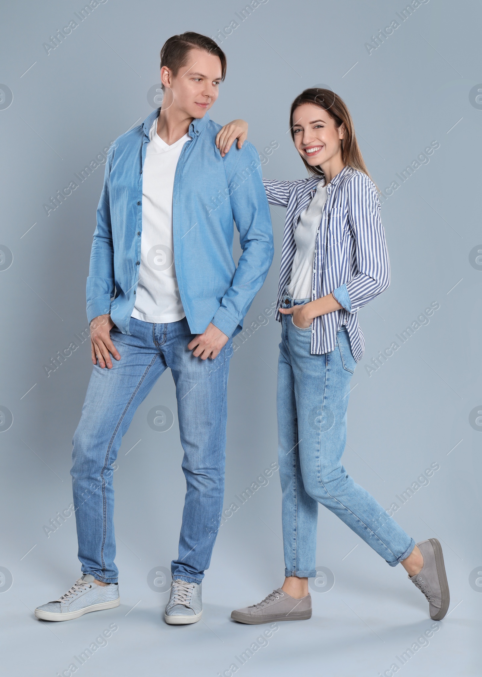 Photo of Young couple in stylish jeans on grey background