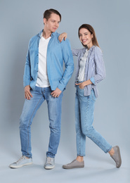 Young couple in stylish jeans on grey background