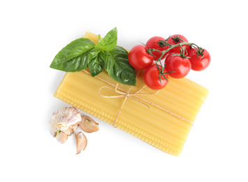 Photo of Uncooked lasagna sheets with cherry tomatoes, garlic and basil isolated on white, top view