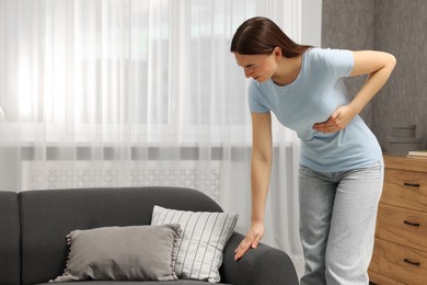 Woman having heart attack near sofa at home