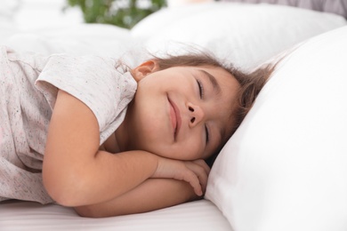 Photo of Cute little girl sleeping on cozy bed