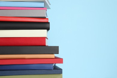 Photo of Stack of different books on light blue background, space for text
