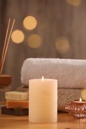 Photo of Spa composition. Burning candles, towels and soap on wooden table, closeup