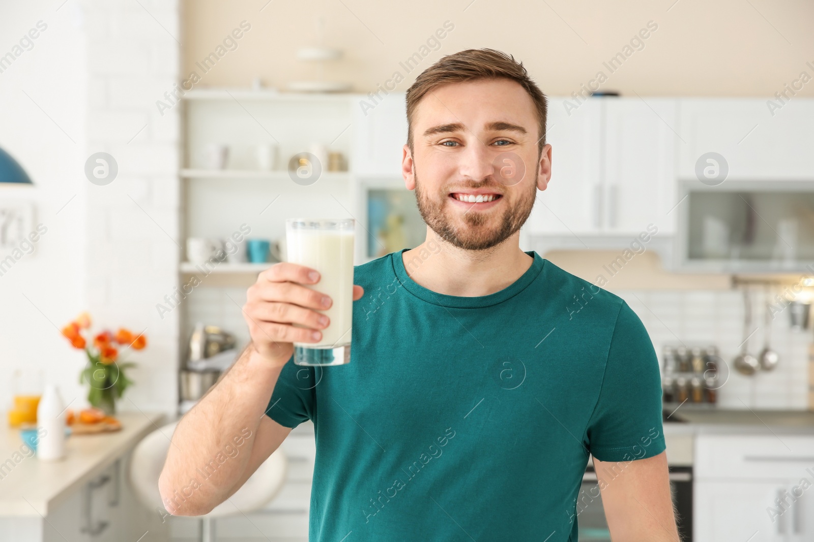 Photo of Young man with glass of tasty milk at home
