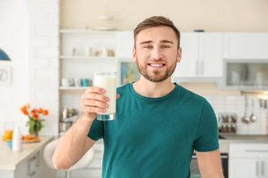 Young man with glass of tasty milk at home