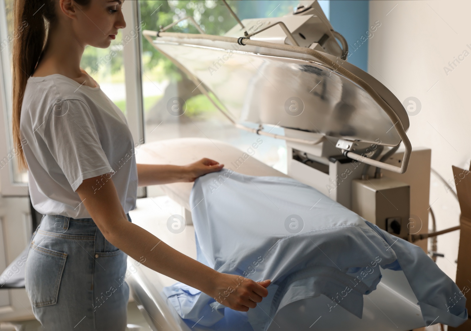 Photo of Female worker using ironing press in dry-cleaning