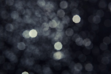 Photo of Silver glitter on dark background. Bokeh effect