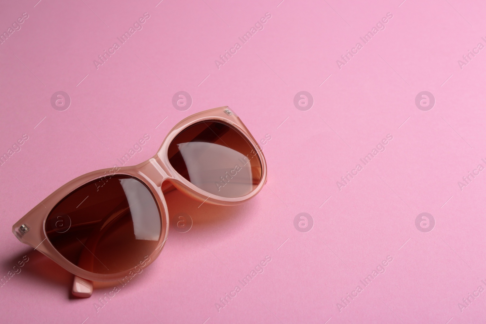 Photo of Stylish sunglasses on pink background, space for text. Fashionable accessory