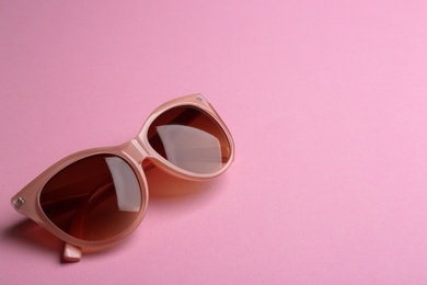 Stylish sunglasses on pink background, space for text. Fashionable accessory