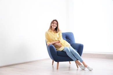 Photo of Young woman sitting in armchair at home. Space for text