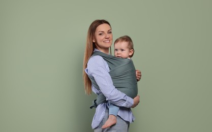 Photo of Mother holding her child in baby wrap on olive background