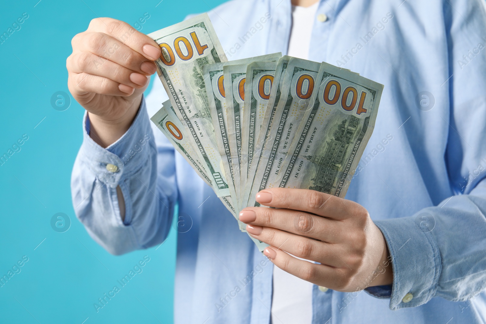 Photo of Woman counting dollar banknotes on turquoise background, closeup. Money exchange concept