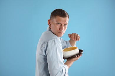 Photo of Greedy man hiding tasty cake on turquoise background