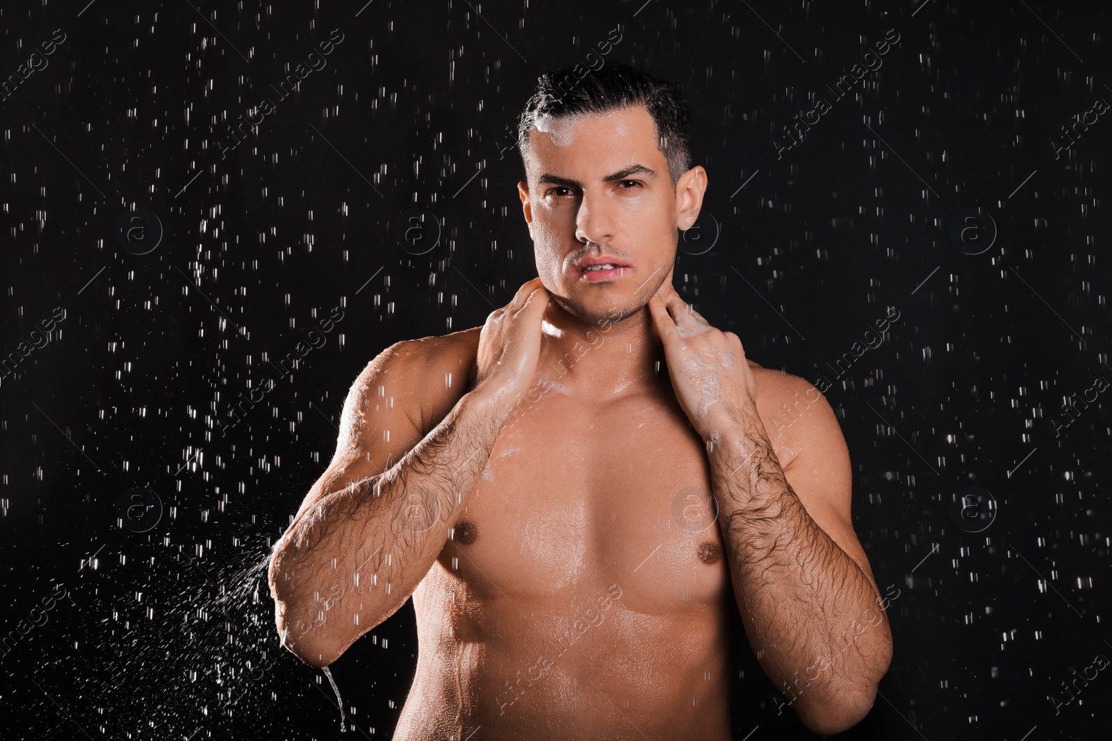 Photo of Man washing hair while taking shower on black background