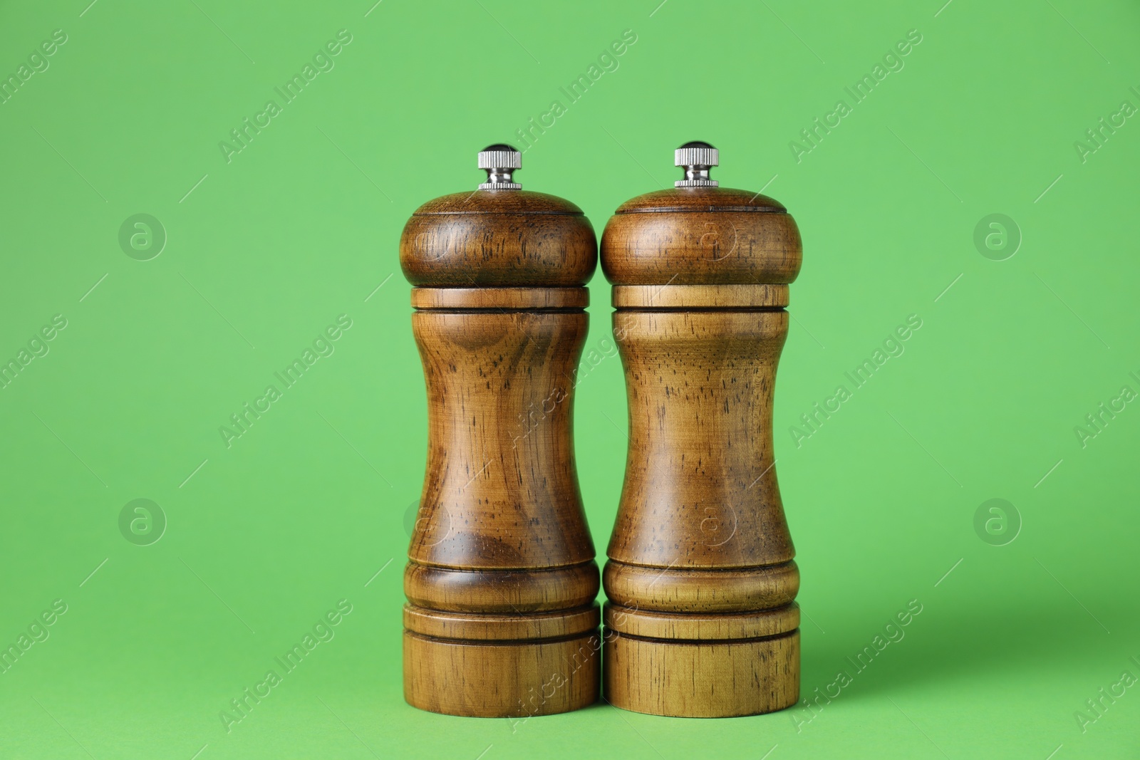Photo of Wooden salt and pepper shakers on green background, closeup
