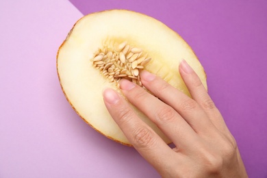 Photo of Young woman touching half of melon on color background, above view. Sex concept