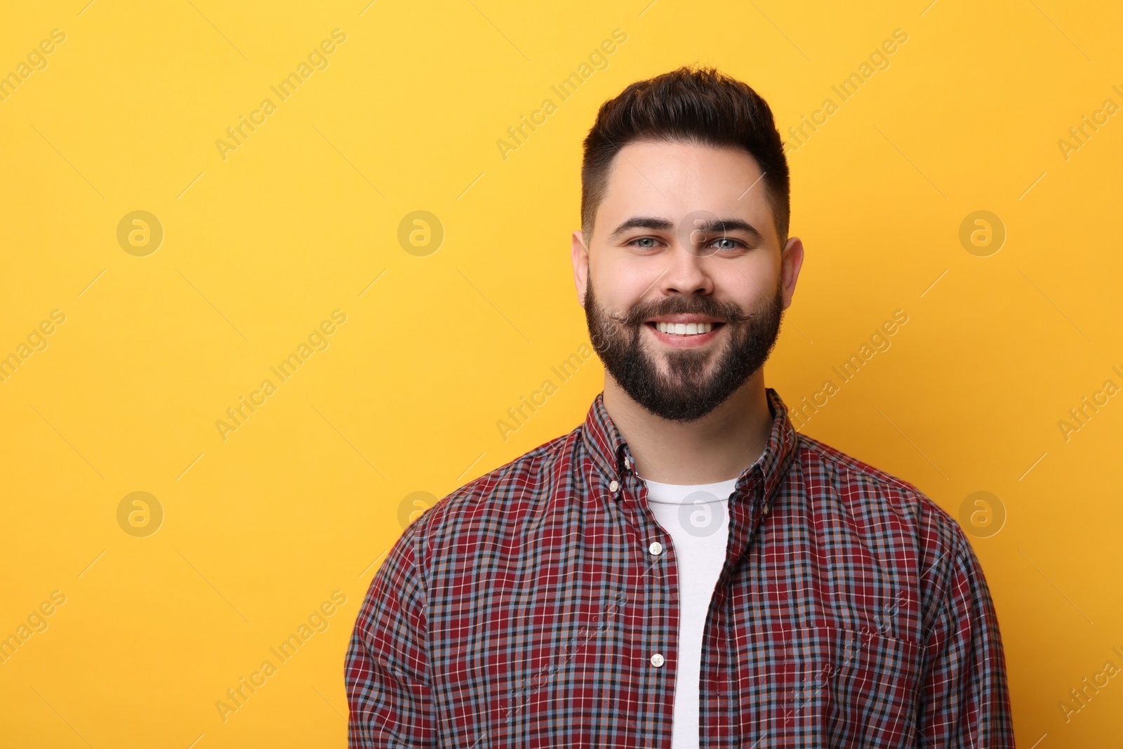 Photo of Portrait of happy young man with mustache on yellow background. Space for text