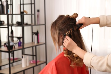 Photo of Stylist working with client in salon, making hairstyle