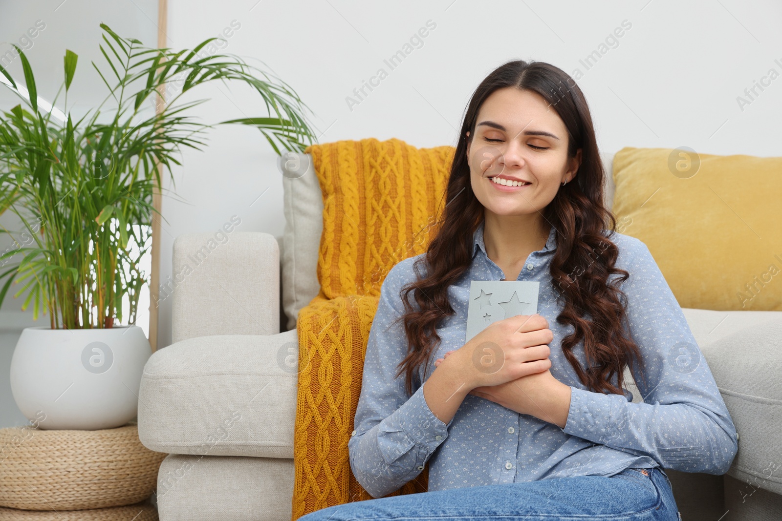 Photo of Young woman with greeting card on floor in living room
