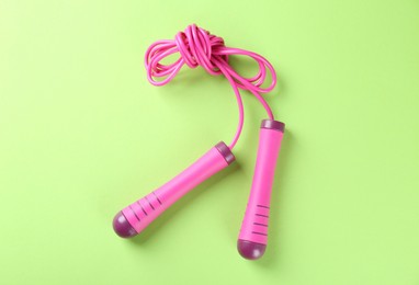 Skipping rope on light green background, top view. Sports equipment