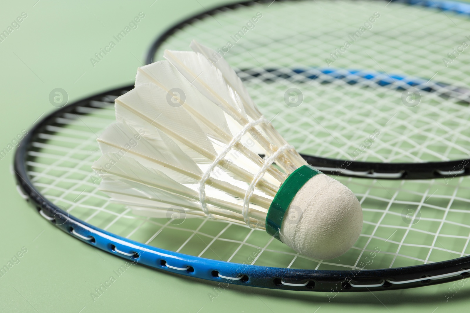 Photo of Feather badminton shuttlecock and rackets on green background, closeup