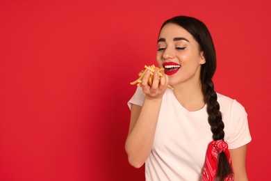 Photo of Beautiful young woman eating French fries on red background. Space for text