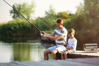 Dad and son fishing together on sunny day