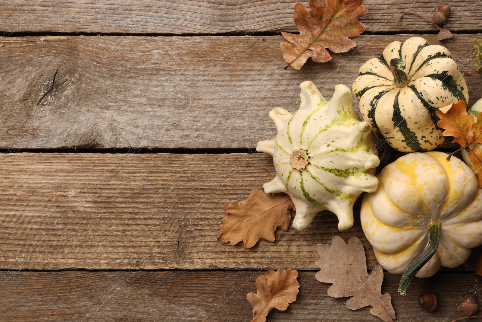 Photo of Fresh ripe pumpkins and dry leaves on wooden table, flat lay. Space for text