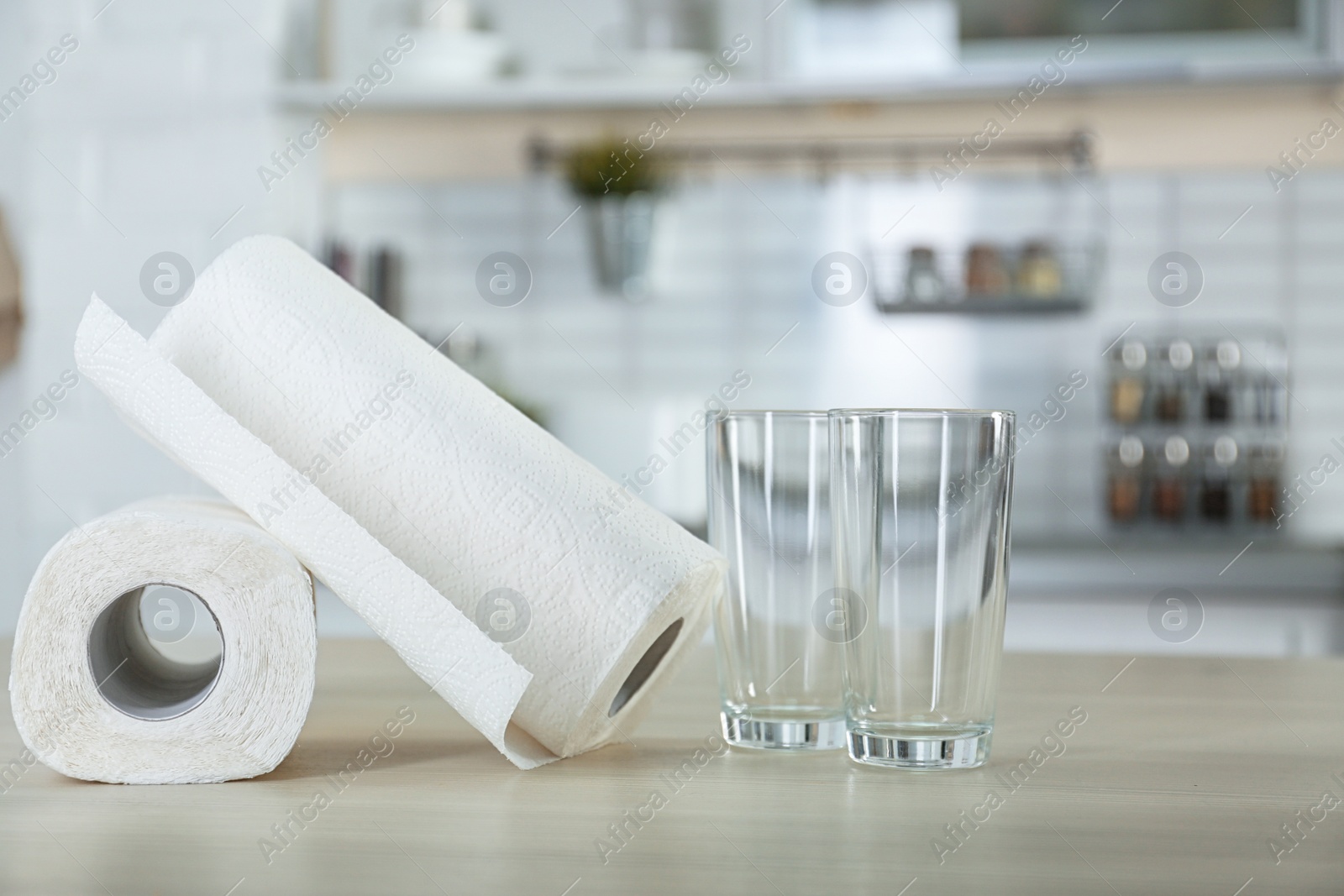 Photo of Rolls of paper towels and glasses on table in kitchen