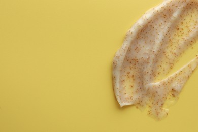 Photo of Sample of face scrub on yellow background, top view. Space for text