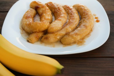 Photo of Delicious fried and fresh bananas on wooden table, closeup