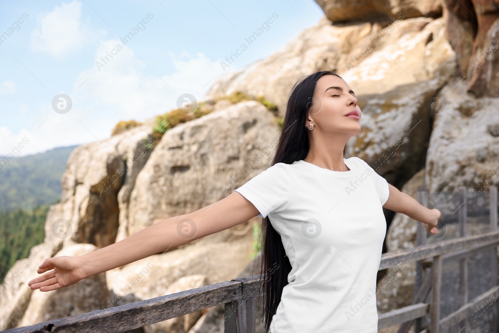 Photo of Feeling freedom. Beautiful woman enjoying nature near wooden railing in mountains