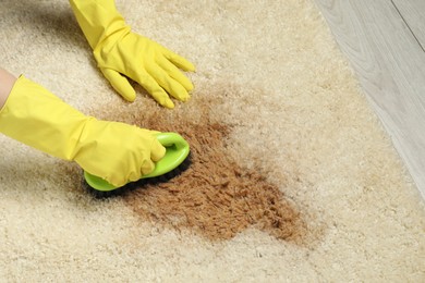 Photo of Woman removing stain from beige carpet, closeup