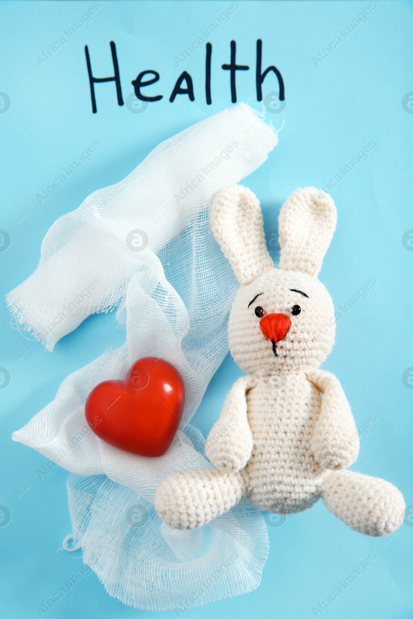 Photo of Flat lay composition with toy bunny, bandage and heart on color background. Children's doctor
