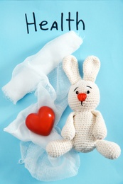 Flat lay composition with toy bunny, bandage and heart on color background. Children's doctor