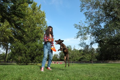 Photo of Woman and her dog playing with flying disk in park