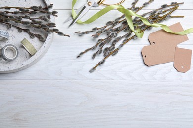 Beautiful pussy willow branches and wrapping materials on white wooden table, flat lay. Space for text